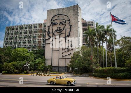 Klassische amerikanische Vorbeifahren ein Gebäude mit einem Che Guevara Wandbild auf der Seite auf dem Platz der Revolution, Havanna, Kuba. Stockfoto