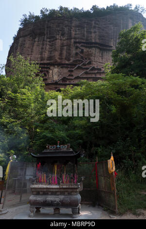 Altar und Räucherstäbchen brennen mit Maijishan Grotten in der Nähe von Tianshui, Gansu Province, China, Asien. Ort, Höhlen und Grotten mit riesigen Buddha und Buddh Stockfoto