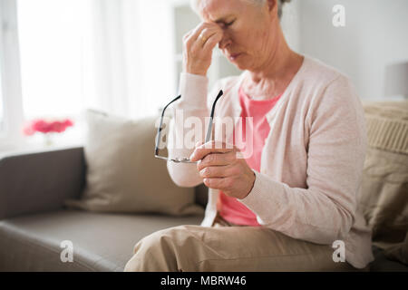 Ältere Frau mit Brille Kopfschmerzen zu Hause in Stockfoto