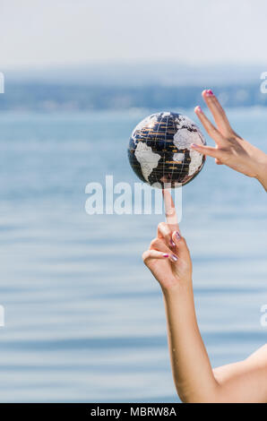 Die Hände der jungen Frau Balancing die Erde auf ihrem Finger - Wasser Ball mit verschiedenen Kontinenten Stockfoto