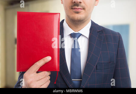 Anonyme Pastor halten roten Bibel oder Notebook als Gläubiger Konzept auf innen Hintergrund Stockfoto