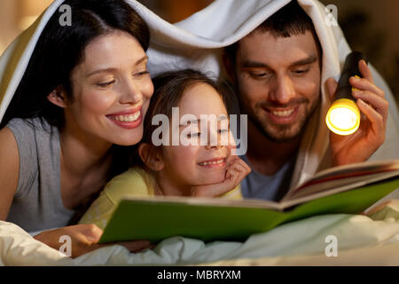 Happy Family lesen Buch nachts im Bett zu Hause. Stockfoto