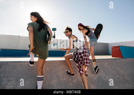 Gerne weibliche Freunde laufen über Skateboard Rampe. Gruppe der weiblichen Skater genießen Skate Park. Stockfoto