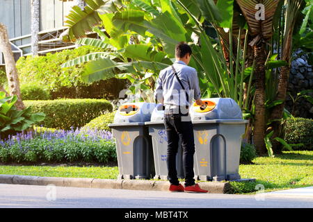 Männer sind Dumping Plastikflaschen Abfälle in Papierkorb Papierkorb bei seitwärts gehen mit Garten öffentliche Stockfoto