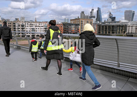 Britische Grundschüler Kinder zu Fuß über die Millennium Bridge Hände mit Lehrer in Süd- London, England UK KATHY DEWITT Stockfoto