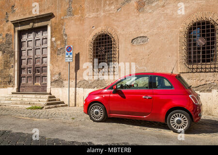 Ein roter Fiat 500 auf einer teilweise gepflasterten Straße im Stadtteil Trastevere in Rom, Italien, ist sie in einen behinderten Parkplatz geparkt, als durch die in der Nähe Vorzeichen dargestellt, Stockfoto