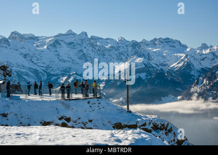 STOOS, Schweiz - Januar 2018 - Eine Gruppe von Touristen und Skifahrer auf der Suche nach schönen verschneiten Alpen aus der Beobachtung Plattform von der Oberseite der Fronalpstock in der Nähe von Stockfoto