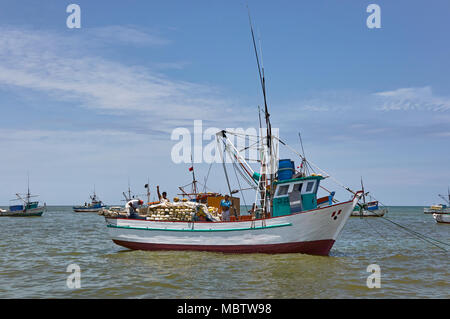 Die lokalen Fischer auf einem peruanischen Fischerboot winken wie unser Boot geht an ihnen vorbei aus Mancora Strand in Peru, Südamerika. Stockfoto