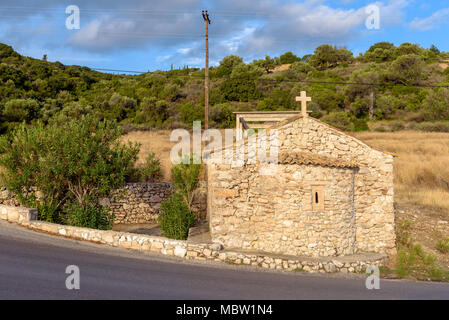 Alte kleine Kapelle in der Nähe der Asphaltstrasse an der Küste der Insel Zakynthos im sonnigen Sommermorgen. Griechenland Stockfoto