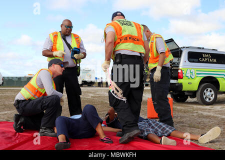 Mitglieder des Miami-Dade Feuerwehr Feuerwehr- und Rettungskräfte, reagieren auf die simulierten Verletzungen eines Freiwilligen bei einer gemeinsamen Übung von der Dade Feuerwehr und Homestead-Miami Speedway in Miami, Fla., Jan. 11, 2018 gehostet wird. Diese jte konzentrierte sich auf den Aufbau von Kapazitäten und der nahtlose Übergang zwischen den örtlichen Ersthelfern und die Unterstützung durch die Nationalgarde und aktiven Soldaten zur Verfügung gestellt. (U. S. Armee Foto von SPC. Samuel Brooks) Stockfoto