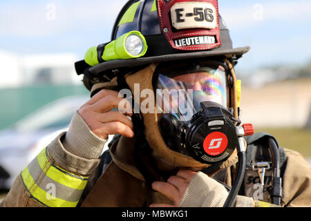 Leutnant José Alfaro der Dade Feuerwehr Hazmat Team, zieht seine Umluftunabhängiges Atemschutzgerät bei einer gemeinsamen Übung von der Dade Feuerwehr und Homestead-Miami Speedway in Miami, Fla., Jan. 11, 2018 gehostet wird. Diese jte konzentrierte sich auf den Aufbau von Kapazitäten und der nahtlose Übergang zwischen den örtlichen Ersthelfern und die Unterstützung durch die Nationalgarde und aktiven Soldaten zur Verfügung gestellt. (U. S. Armee Foto von SPC. Samuel Brooks) Stockfoto