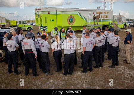 Dade Feuerwehr Gefahrgut-Mitglieder, diskutieren über die simulierten Masse chemischer Angriff bei einer gemeinsamen Übung von der Dade Feuerwehr und Homestead-Miami Speedway in Miami, Fla., Jan. 11, 2018 gehostet wird. Diese jte konzentrierte sich auf den Aufbau von Kapazitäten und der nahtlose Übergang zwischen den örtlichen Ersthelfern und die Unterstützung durch die Nationalgarde und aktiven Soldaten zur Verfügung gestellt. (U. S. Armee Foto von SPC. P.J. Siquig) Stockfoto