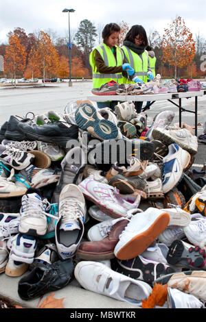 Zwei jugendlich freiwilliger Art durch Tennis Schuhe vor dem Werfen in einen Haufen von Sneakers am 23. November recycelt werden, 2013 in Lawrenceville, GA. Stockfoto