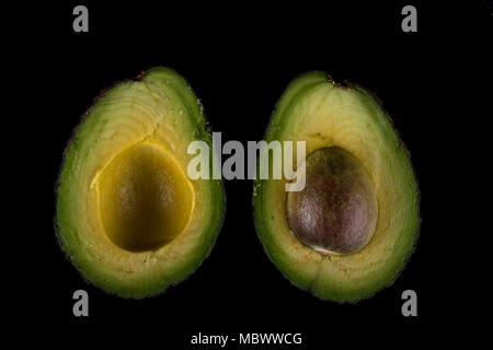 Zwei Hälften eines Avocado mit Schnittmarken. Auf schwarzem Hintergrund Stockfoto