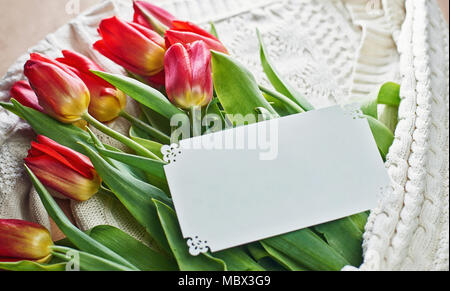 Die Pullover liegt auf Kraftpapier und hält Tulpen mit einem Buchstaben (Platz für Text) Stockfoto