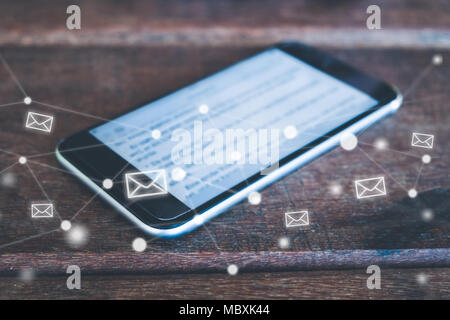 Smartphone auf dem Schreibtisch mit dem Buchstaben Symbole. e-mail/e-mail Konzept auf Handy Stockfoto