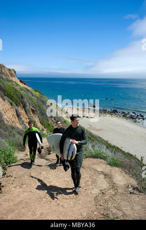 Surfer klettert Trail auf Felsen über dem Strand in der Nähe von Malibu, CA Stockfoto