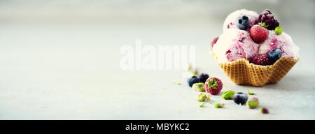 Rosa Eis mit Beeren, Erdbeeren, Blaubeeren, Himbeeren, Pistazien im Waffle basket. Sommer essen Konzept, kopieren. Gesund glutenfreie Obst Eis. Banner Stockfoto