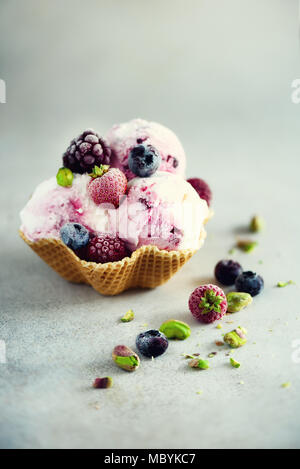Rosa Eis mit Beeren, Erdbeeren, Blaubeeren, Himbeeren, Pistazien im Waffle basket. Sommer essen Konzept, kopieren. Gesund glutenfreie Obst Eis Stockfoto