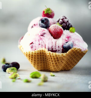 Rosa Eis mit Beeren, Erdbeeren, Blaubeeren, Himbeeren, Pistazien im Waffle basket. Sommer essen Konzept, kopieren. Gesund glutenfreie Obst Eis Stockfoto