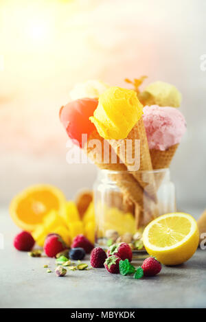 Bunte Eis Kugeln in Waffeln mit verschiedenen Geschmacksrichtungen - Mango, Limette, Minze, Pistazie, Orangen, Erdbeeren, Himbeeren, Blaubeeren. Sommer Konzept Stockfoto
