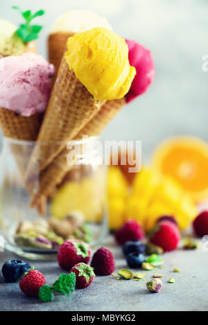 Bunte Eis Kugeln in Waffeln mit verschiedenen Geschmacksrichtungen - Mango, Limette, Minze, Pistazie, Orangen, Erdbeeren, Himbeeren, Blaubeeren. Sommer Konzept Stockfoto