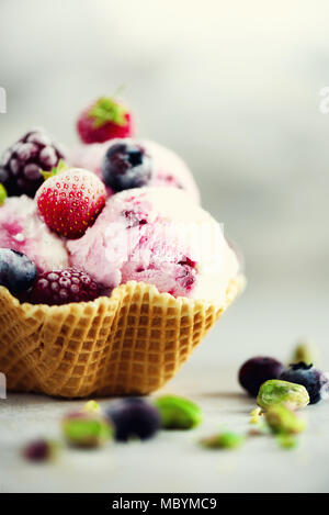Rosa Eis mit Beeren, Erdbeeren, Blaubeeren, Himbeeren, Pistazien im Waffle basket. Sommer essen Konzept, kopieren. Gesund glutenfreie Obst Eis. Banner Stockfoto