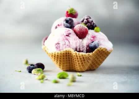 Rosa Eis mit Beeren, Erdbeeren, Blaubeeren, Himbeeren, Pistazien im Waffle basket. Sommer essen Konzept, kopieren. Gesund glutenfreie Obst Eis. Banner Stockfoto