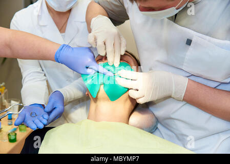 Eine latex-Platte, die den Zahn vom Rest der Mundhöhle während der Bestrahlung zu behandeln, zu isolieren. Bereiten Zahnärzte Zahn ein Meer zu installieren. Stockfoto