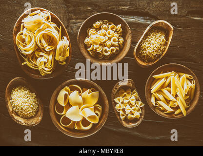 Verschiedene pasta Arten in hölzernen Schüsseln auf den Tisch. Ansicht von oben. Stockfoto