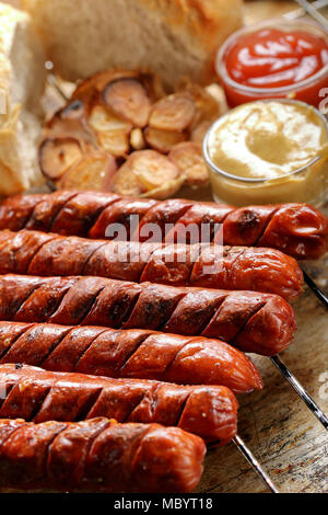 Gegrillte Würstchen mit Sauce Ketchup und Senf auf metall gitter Stockfoto