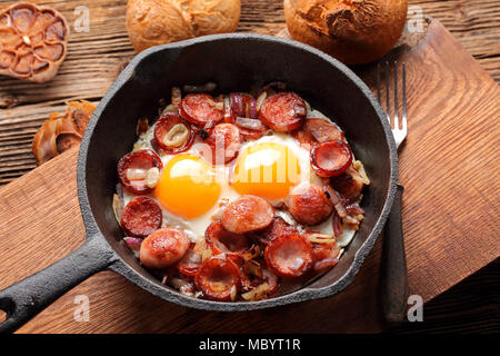 Spiegeleier mit Wurst und Zwiebeln in der Pfanne Stockfoto