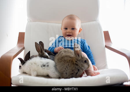 Wenig Kleinkind Kind, baby boy, spielen mit Hasen und Ostereier zu Hause, bunte hand Zeichnungen auf den Eiern Stockfoto