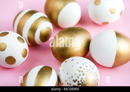 Nahaufnahme von Ostern Eier gefärbt mit goldenen Farbe. Verschiedene gestreifte und gepunkteten Designs. Rosa Hintergrund. Stockfoto