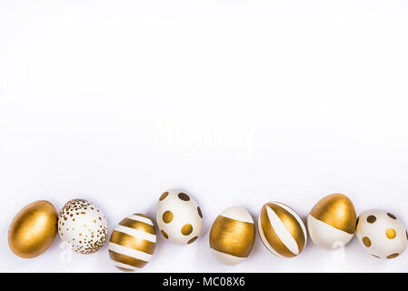 Blick von oben auf die Ostereier gefärbt mit goldenen Farbe in verschiedenen Mustern. Verschiedene gestreifte und gepunkteten Designs. Weißer Hintergrund. Kopieren Sie Platz. Stockfoto