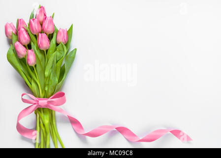 Blick von oben auf die rosa Tulpen Blumenstrauß, mit rosa Schleife über weißen Hintergrund gewickelt. Kopieren Sie Platz. Stockfoto