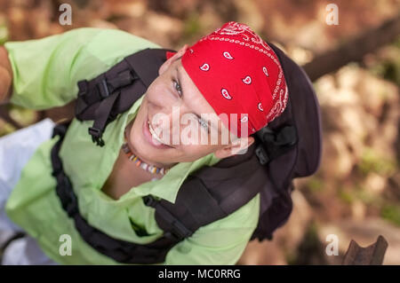 Blick von oben auf den jungen Mann mit grünen Hemd, rotes Halstuch suchen und lächelnd, tragen, Rucksack. Stockfoto