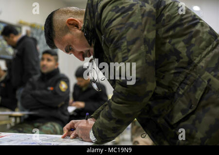 Die irakischen Sicherheitskräfte Maj. Alaa, Assistant Instructor für das irakische Forward Air Controller, Grundstücke Koordinaten einer Karte während der Überprüfung in Bagdad Kampfschule, Camp Taji, Irak, Jan. 15, 2017. Ausbildung auf den Aufbau der Kapazitäten Websites ist ein integraler Bestandteil der Combined Joint Task Force - Betrieb die Lösung der globalen Koalition, um die irakischen Sicherheitskräfte, um Mitarbeiter zu schulen ISIS zu besiegen. (U.S. Armee Foto von SPC. Audrey Ward) Stockfoto