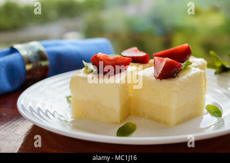 Feine Hüttenkäse und cremig Souffle in Form von Würfeln, Verzieren mit Minze und frischen Erdbeeren auf einer weißen Platte Stockfoto