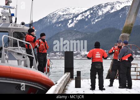 Mitglieder der Coast Guard Station Juneau haben eine Diskussion vor Beginn der Mann über Bord Ausbildung in Juneau, Alaska, Jan. 24, 2018. Station Juneau durchgeführt, um die Mann-über-Bord-Position Bohrer bei Frost zu erhalten neue Mitglieder boatcrew qualifiziert. U.S. Coast Guard Foto von Petty Officer 1st Class Jon-Paul Rios. Stockfoto