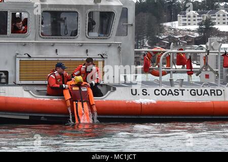 Mitglieder der Coast Guard Station Juneau ein Dummy ziehen aus dem Wasser beim Leiten der Mann über Bord Ausbildung in Juneau, Alaska, Jan. 24, 2018. Station Juneau durchgeführt, um die Mann-über-Bord-Position Bohrer bei Frost zu erhalten neue Mitglieder boatcrew qualifiziert. U.S. Coast Guard Foto von Petty Officer 1st Class Jon-Paul Rios. Stockfoto