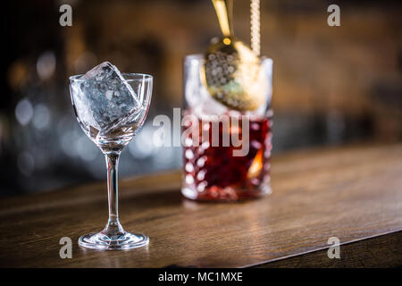 Manhattan Cocktail trinken am Tresen im Pub oder Restaurant. Ice Cube in leeren Glas. Stockfoto