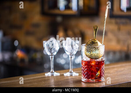 Manhattan Cocktail trinken am Tresen im Pub oder Restaurant. Ice Cube in leeren Glas. Stockfoto