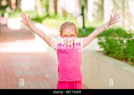 Glückliche kleine Mädchen mit Face Art malen im Park. Geburtstag des Kindes masquerade Party Spaß haben, Lachen. Unterhaltung und Urlaub. Stockfoto