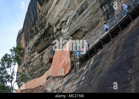 Horizontale Ansicht von Touristen auf dem Weg an der Seite der Klippe in Sigiriya oder Lions Rock in Sri Lanka festhalten. Stockfoto