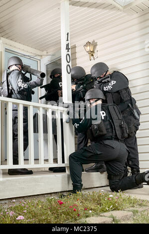 Polizei taktische oder swat Team versammelt, die Tür eines Hauses mit gezogenen Waffen und Schutzkleidung für die Simulation eines Haftbefehls oder Geisel Stand-off s Stockfoto