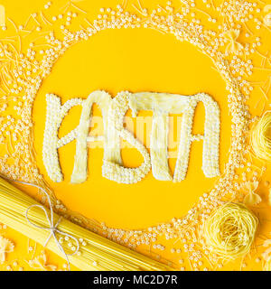 Das Wort "Pasta wird in umfangreichen Briefe von kleinen rohen Makkaroni in einem Kreis unter verschiedenen Arten von Nudeln. Essen auf einem hellen Hintergrund Stockfoto