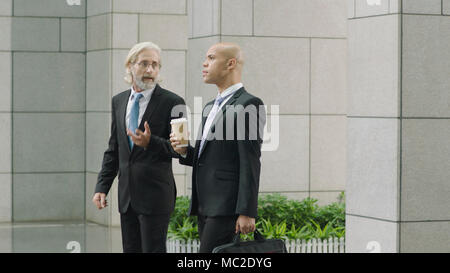 Kaukasische und Latino Führungskräfte Diskussion von beim Gehen in einem modernen Bürogebäude. Stockfoto