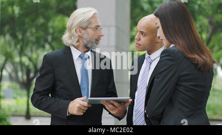 Multinationale Unternehmen Führungskräfte diskutieren Geschäft mit digitalen Tablet. Stockfoto