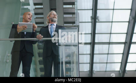 Zwei design Professionals in modernes Gebäude aus Glas und Stahl in eine Diskussion über digitale Tablet stehen. Stockfoto